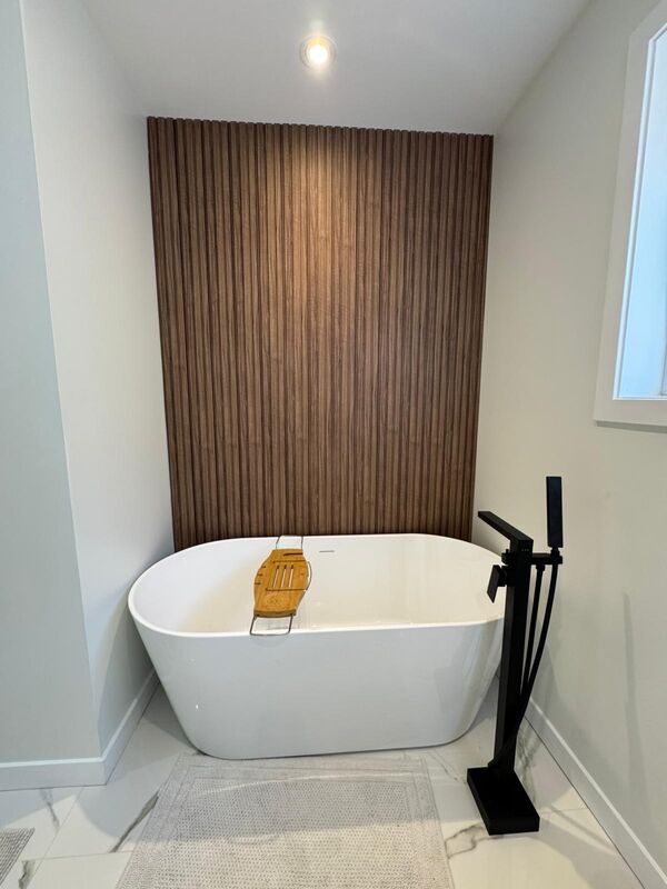 Modern white bathtub with a brown wood wall in the background