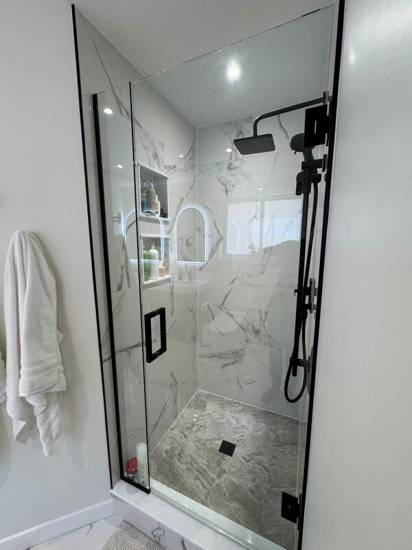 Glass door stand-up shower with modern black accent pieces